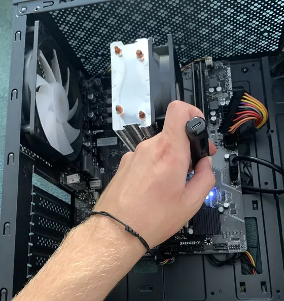 Mão do Gustavo dentro de um gabinete, montando um computador