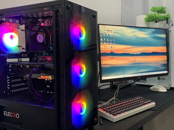 Computador montado para um cliente, com as ventoinhas coloridas acesas, ao lado do monitor