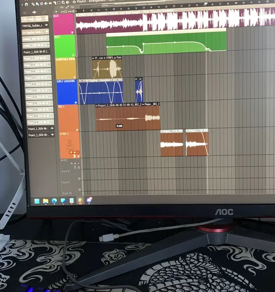 Monitor com um programa de produção musical aberto e teclado iluminado